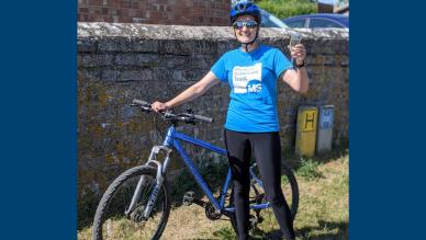 Kate holding prosecco next to her bike after completing Miles for MS