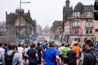 image of a group of runners facing away from the camera running up a foggy road in Edinburgh