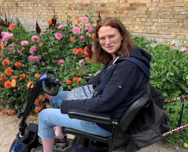 white women with brown hair in a mobility scooter in a flower garden