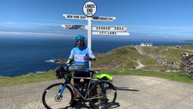man with bicycle at a sign at "Lands End"