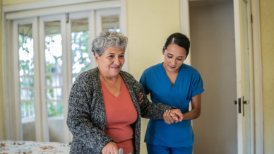 Female nurse supporting a woman with walking