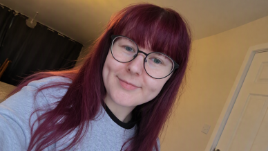 lady with red hair and glasses smiling