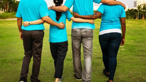 Four people linking arms while walking away