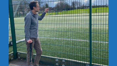 Andy with a walking stick looking out at a football pitch