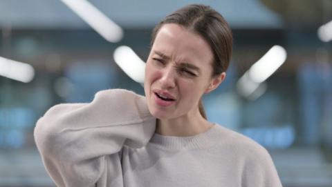 Woman hold the back of her neck as she experiences Lhermitte’s sign