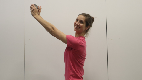 Laura from Neuro Heroes lifting a tin of bean in two hands above her head.