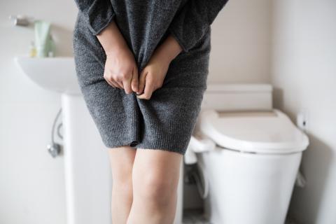 Person standing with crossed legs next to toilet