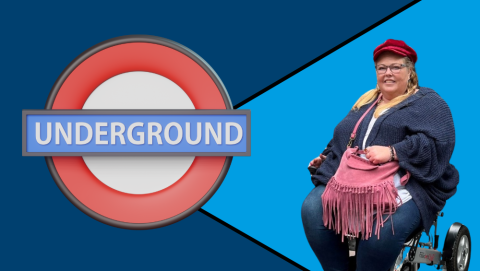 Antoinette in a powered wheelchair next to a London Underground sign