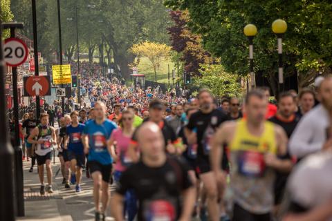 blurred image of a large group of runners running up a road in London