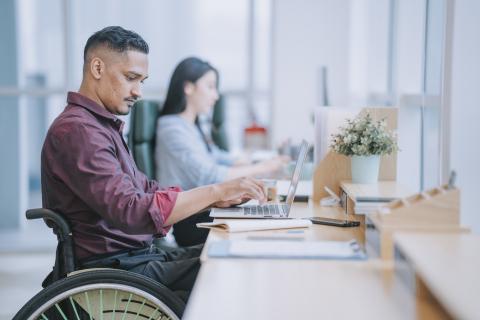 an office worker in a wheelchair at their desk