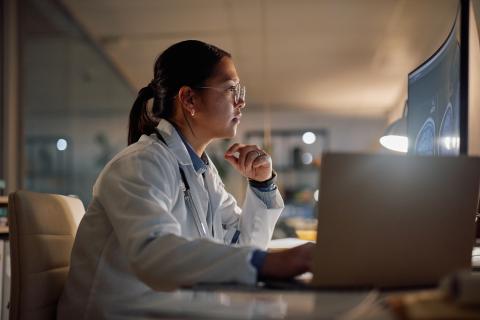 Researcher in lab coat looking at MRI scan