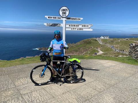man with bicycle at a sign at "Lands End"