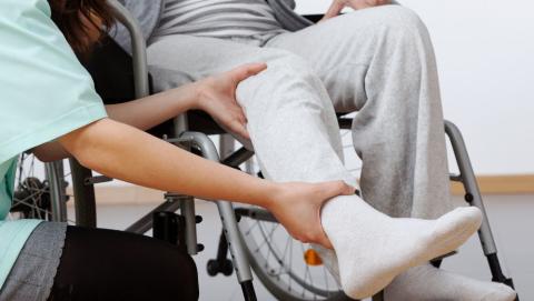 Therapist assessing the leg stiffness of someone sat in a wheelchair