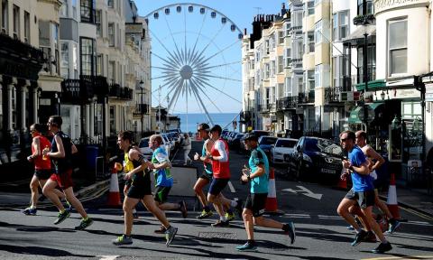 runners participating in the Brighton Marathon in front of a Ferris wheel