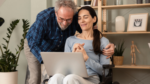 woman in a wheelchair using her laptop with her husband