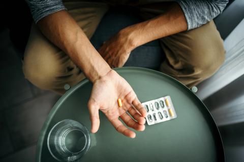 Man holding pill in palm of hand
