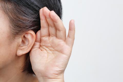 Person holding their hand to their ear