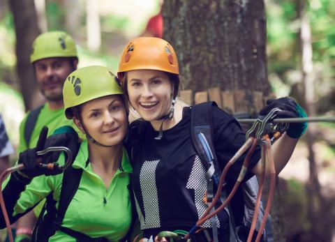 Two women smiling at camera with helmets and harnesses on