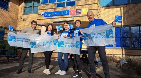 group of people holding MS Trust banners in front of an office