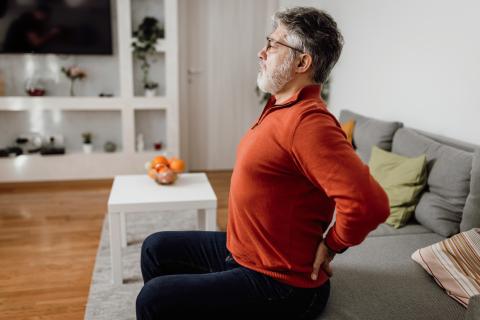 Man on sofa holding lower back