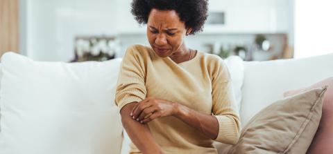 Woman scratching arm looking confused