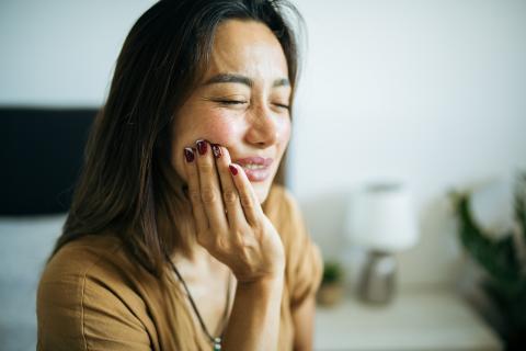 Woman holding cheek in pain with trigeminal neuralgia