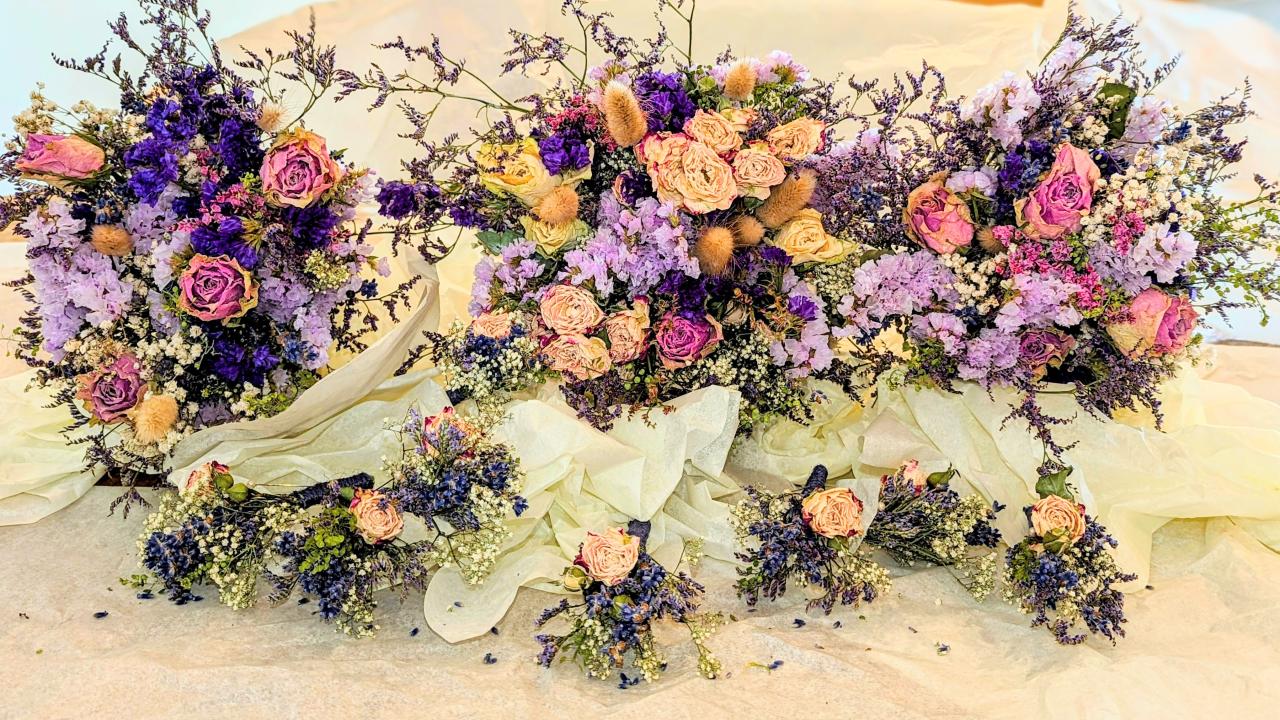Three large bouquet's of dried flowers full of roses, pinks, purples, blues and beige. Wrapped in an off-white tissue paper.